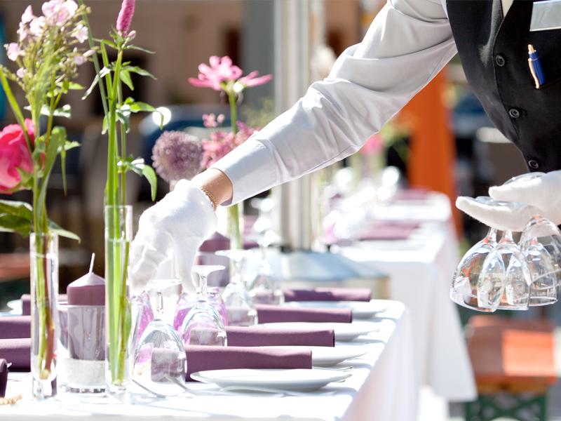 Waiter in white gloves at a laid table