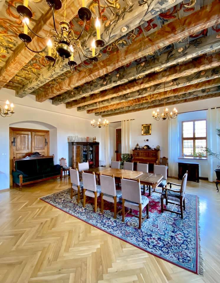 Saal mit bemalter Decke, Kronleuchtern und langer Tafel