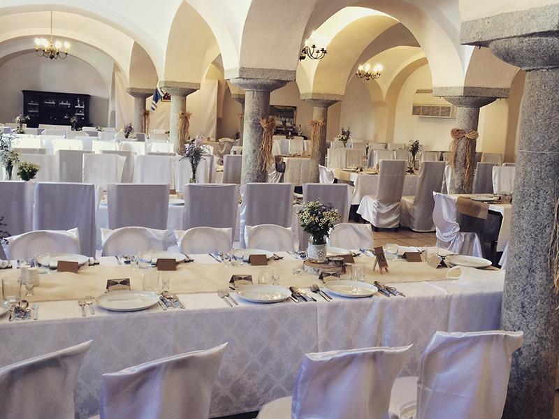 Saal mit Säulen und weißen Stühlen, für ein Fest gedeckt