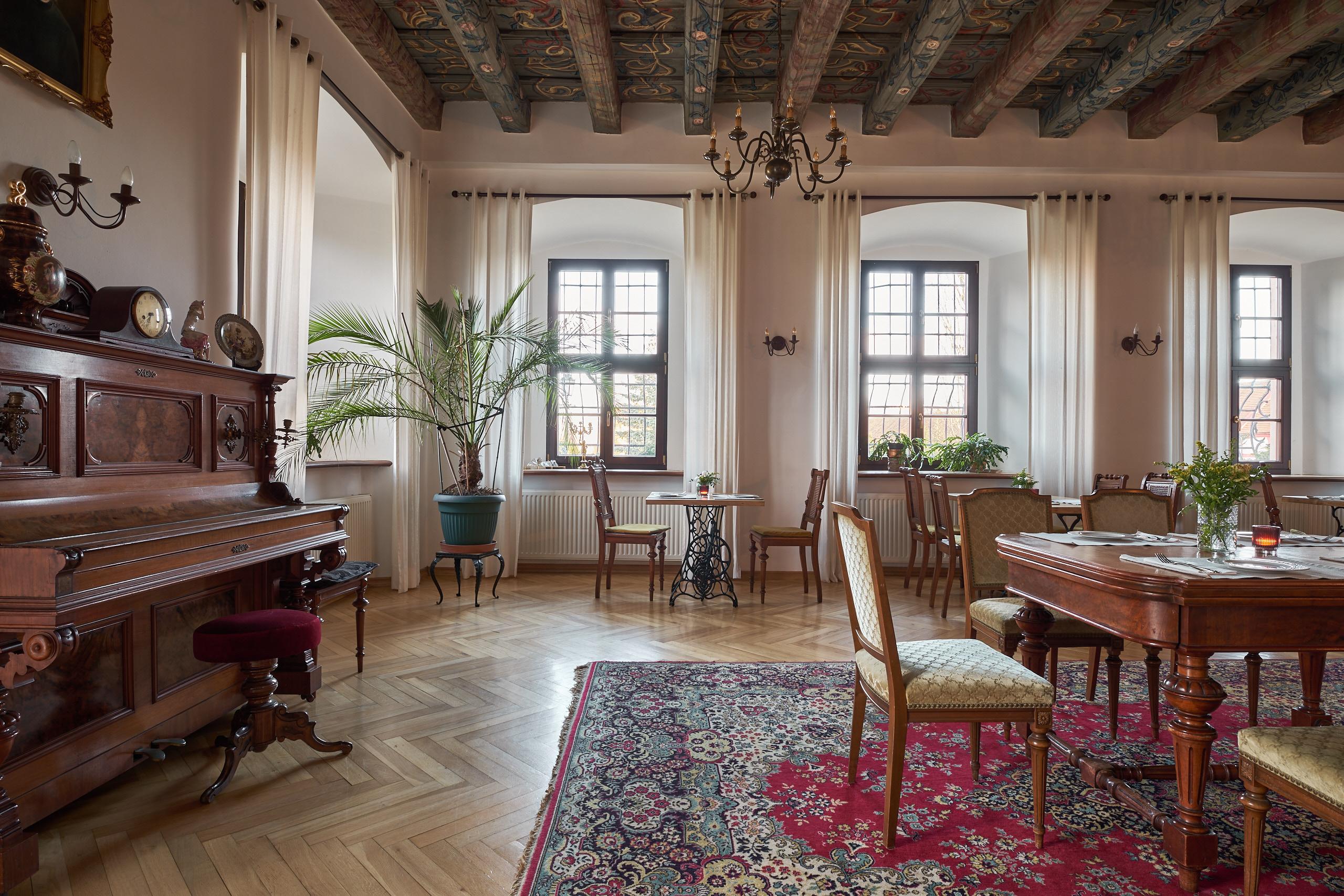 Schlosssalon mit Balkendecke, Tischen und antiken Möbeln