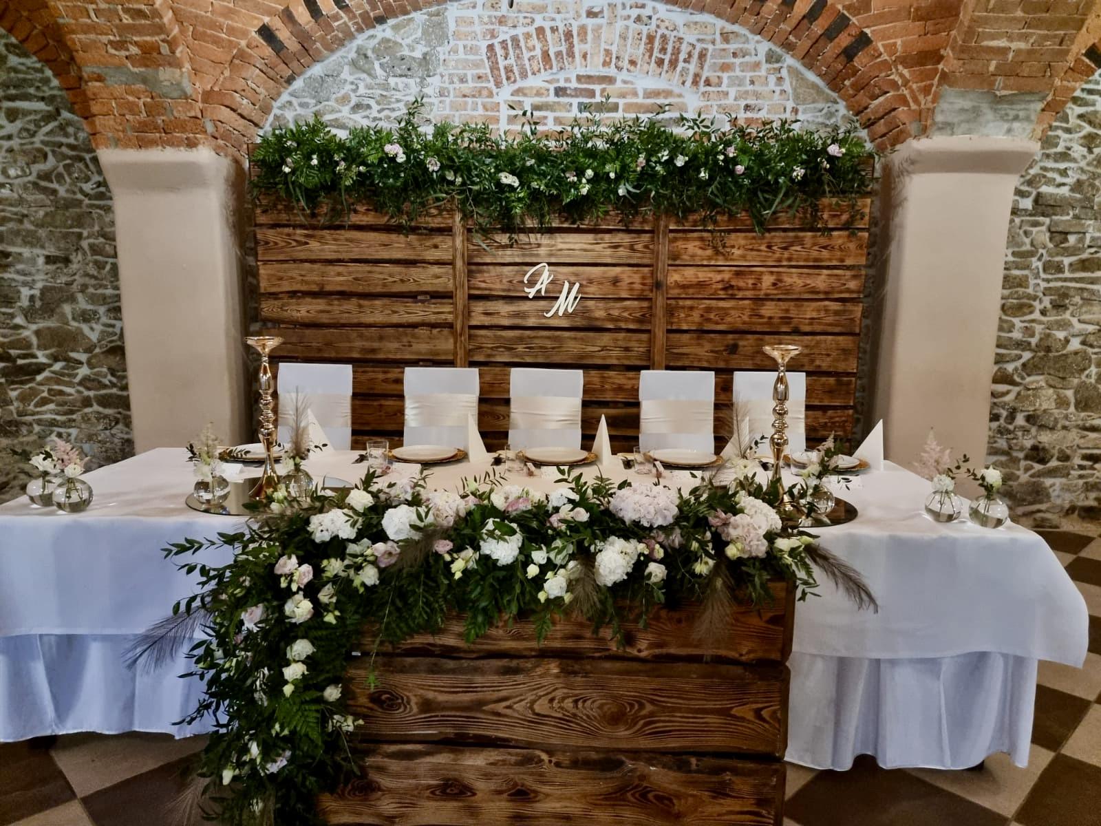 Brauttisch mit weißen Blumen vor einer Natursteinwand