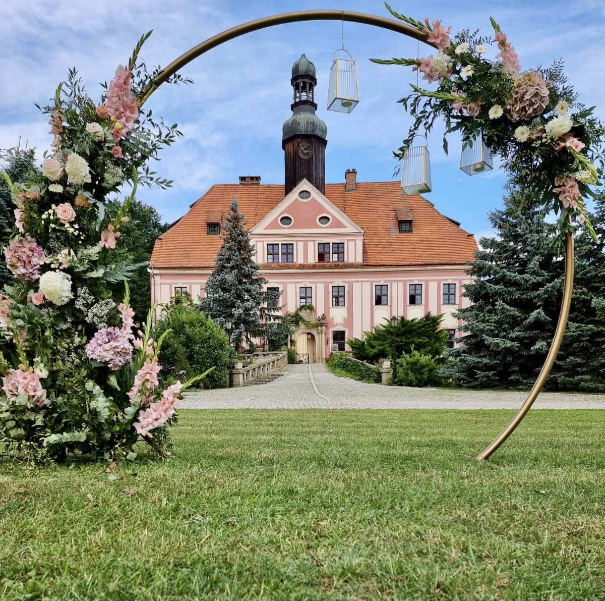 Floral wedding arch on the lawn with the palace behind