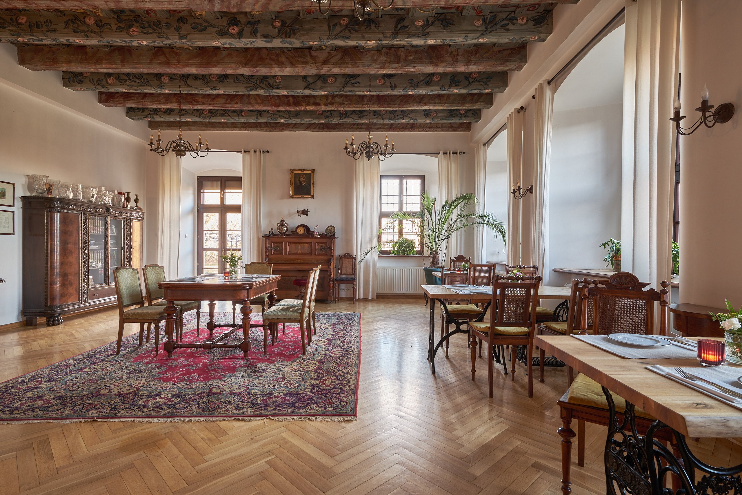 Spacious salon with a red rug and tables by the windows