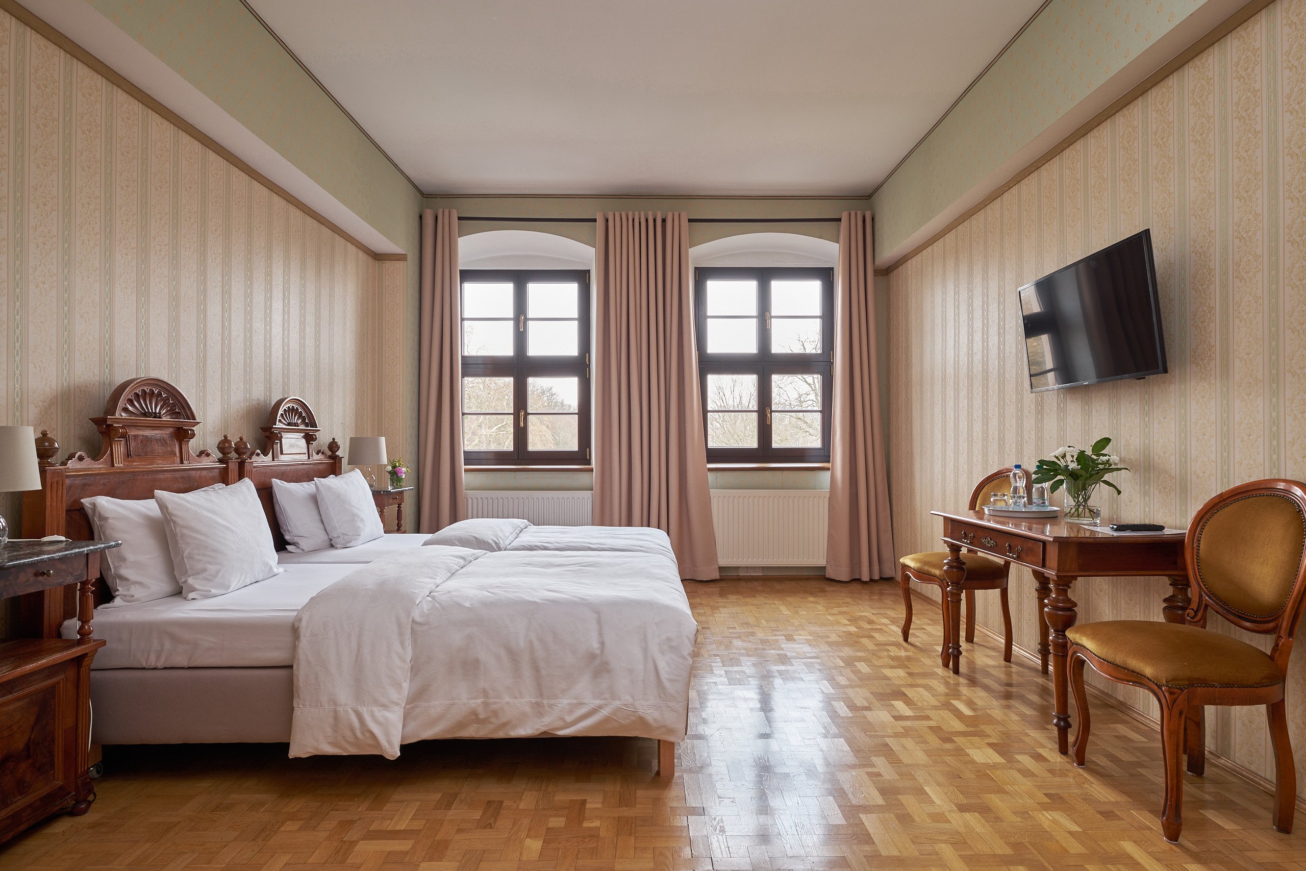 Goldenes Zimmer: zwei Stilbetten, Schreibtisch und zwei Fenster zum Park